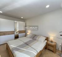 Světlá ložnice v 1-pokojovém bytě s podlahou s dřevěným dekorem a vestavěnou skříní.