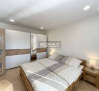 Ložnice s podlahou s dřevěným dekorem v 1-pokojovém bytě, světlá postel a šatník.