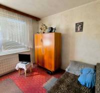 Pokoj v 3-pokojovém bytě se skříní, pohovkou a malou obrazovkou.