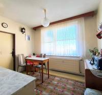 Jídelna s jednoduchým nábytkem v 3-pokojovém bytě, podlaha s dekorativním kobercem.