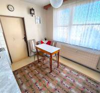 Kuchyně ve 3-pokojovém bytě s jídelním stolem, křesly a kobercem.