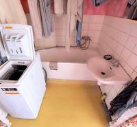 Koupelna s umyvadlem, vanou a pračkou v 3-pokojovém bytě.