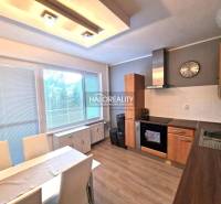 Kuchyně ve 3-pokojovém bytě s podlahou s dřevěným dekorem a jídelním stolem.