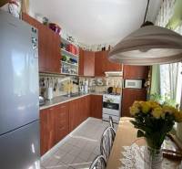 Rustikální kuchyně v 2pokojovém bytě s jídelním stolem a plnými policemi.