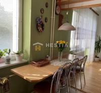 Jídelna s dřevěným dekorem, zelenými stěnami, květinami a stolem v dvoupokojovém bytě.