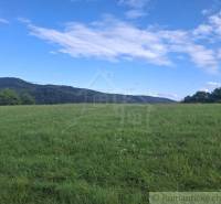 Zelená louka s kopci a oblohou v Horním Tisovníku, vhodná pro pozemky - bydlení.