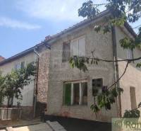 Rodinný dům v Šiatorské Bukovince, obklopený zelení a stromy, se šikmou střechou.