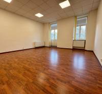 Prázdná kancelář s podlahou s dřevěným dekorem a velkými okny.