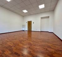 Kancelář s podlahou s dřevěným dekorem, bílými stěnami a podhledovým stropem.