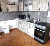 Kuchyně s dlažbou a kuchyňskou linkou v 2-pokojovém bytě.