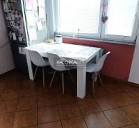 Kuchyně 2pokojového bytu s jídelním stolem, bílými židlemi a oknem.