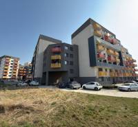 Bytové domy na Mikovíniho ulici v Trnavě s parkovištěm a zelenou plochou.