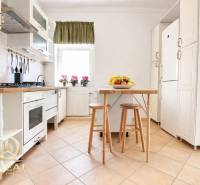 Kuchyně v 1-pokojovém bytě s bílými skříňkami a stolem s ovocem.