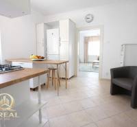 Kuchyně s barovým pultem v 1-pokojovém bytě a ovocem na stole.