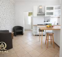 Kuchyně s barovým pultem, ovocem a křesly v 1-pokojovém bytě.