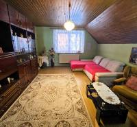 Obývací pokoj s kobercem, pohovkou a podlahou s dřevěným dekorem v rodinném domě.