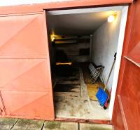 Garáž v rodinném domě v Kameňanech s otevřenými kovovými dveřmi a nářadím.