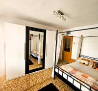 Ložnice v rodinném domě s postelí, kobercem a skříní se zrcadlem.