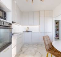 Kuchyně ve 3-pokojovém bytě s bílými skříňkami a kamennou podlahou.