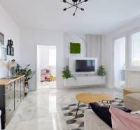 Obývací pokoj v 3-pokojovém bytě s dekorativním stolem a televizí na stěně.