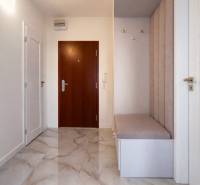 Vstupní chodba v 3-pokojovém bytě s dlažbou a čalouněnou lavicí.