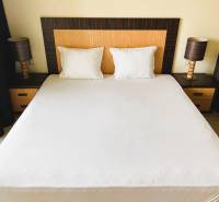 Postel s dvěma nočními stolky a lampami, 1-pokojový byt.