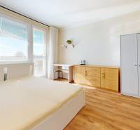 Světlá ložnice v 1-pokojovém bytě s podlahou s dřevěným dekorem, skříní a postelí.