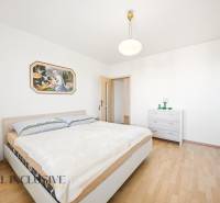 Ložnice s podlahou s dřevěným dekorem v rodinném domě a obrazem na stěně.