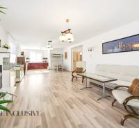 Obývací pokoj v rodinném domě s podlahou s dřevěným dekorem a světlým nábytkem.