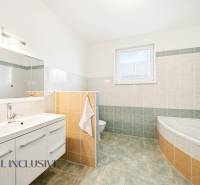 Koupelna s vanou, zrcadlem a úložným prostorem v rodinném domě.