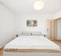 Ložnice v rodinném domě s jednoduchým nábytkem a podlahou s dřevěným dekorem.