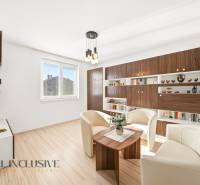 Obývací pokoj v rodinném domě s bílými křesly a podlahou s dřevěným dekorem.