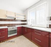 Kuchyně v rodinném domě s červenými skříňkami a spotřebiči.