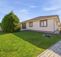 Rodinný dům v Kútnikoch s trávníkem, stromy a dlažbou.