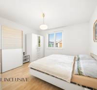 Ložnice v rodinném domě s podlahou s dřevěným dekorem, bílým nábytkem a obrazem.