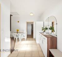 Interiér rodinného domu s bílým stolem a židlemi, s velkým zrcadlem na stěně.