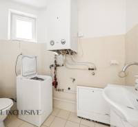 Koupelna v rodinném domě s bojlerem, pračkou a umyvadlem.