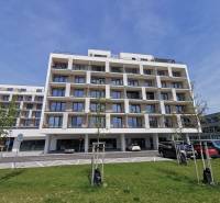 Bytový dům na ulici Eduarda Wenzla s parkováním a garážemi v popředí.