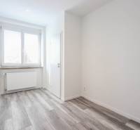 Světlý pokoj s podlahou s dřevěným dekorem a oknem v 3-pokojovém bytě.