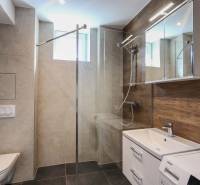 Koupelna v 3-pokojovém bytě s moderní sanitou a podlahou s dřevěným dekorem.