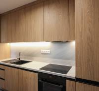 Kuchyně v 3-pokojovém bytě s dřevěným dekorem kuchyňské linky a zabudovanými spotřebiči.