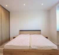 Ložnice v 3pokojovém bytě s postelí a vestavěnou skříní s dřevěným dekorem.