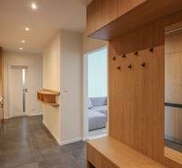 Chodba s podlahou s dřevěným dekorem a šatníkovými skříněmi v 3-pokojovém bytě.