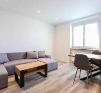 Obývací pokoj s rohovou sedačkou, jídelním stolem a podlahou s dřevěným dekorem.