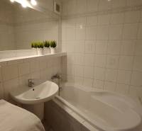 Koupelna s vanou a umyvadlem v 3-pokojovém bytě, bílé obklady a dekorace.