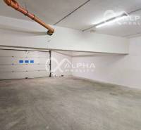 Garáž v 2-pokojovém bytě, s betonovou podlahou a rolovací bránou.