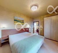 Ložnice v 2pokojovém bytě s postelí, skříní a obrazem na stěně.