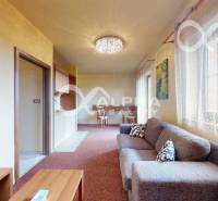 Obývací pokoj v 2-pokojovém bytě s pohovkou a jídelním stolem.