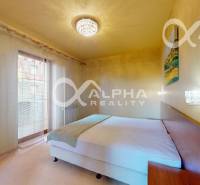 Ložnice v 2-pokojovém bytě se závěsy a lustrem, postelí a nočními stolky.