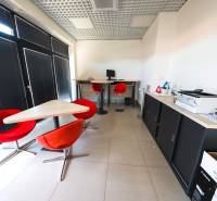 Kanceláře s červenými židlemi a počítačem, podlaha s dlažbou.